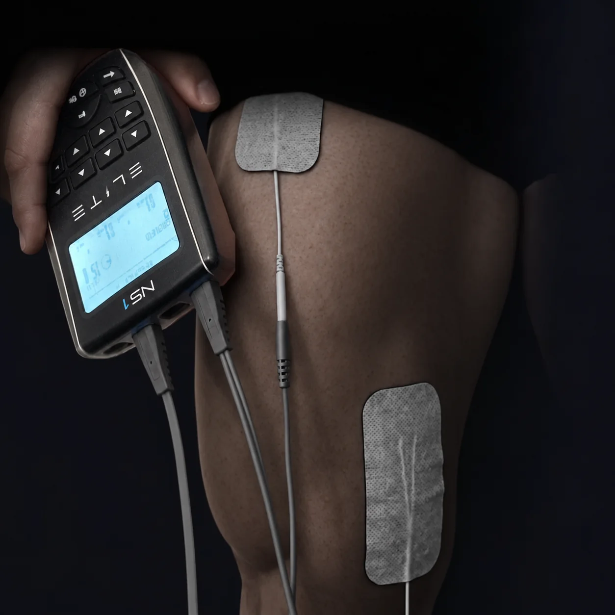 The NS1 with its label and Elite wordmark, beside electrode pads on a leg