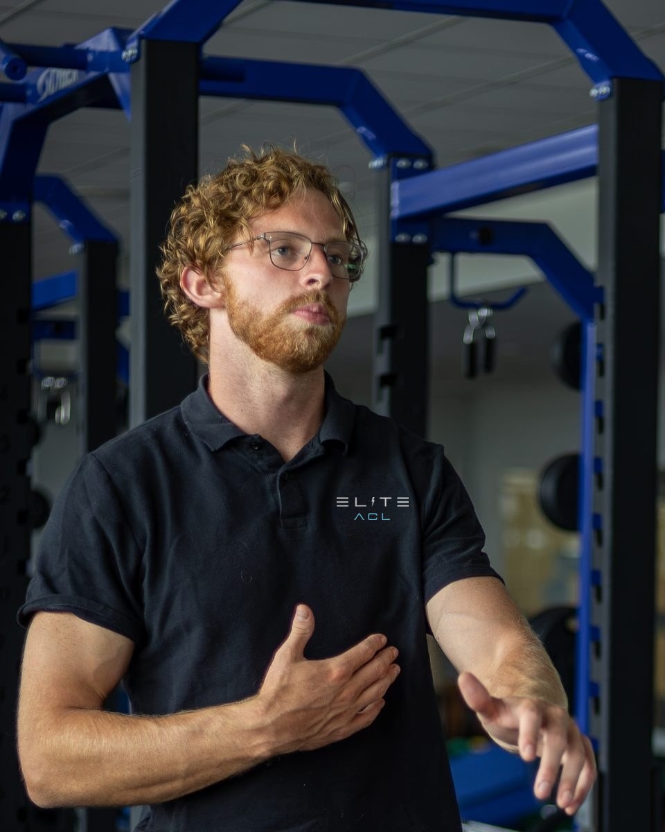 Zach Jungels coaching an athlete in a weight room